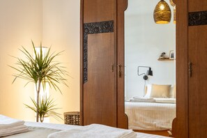 Una camera d'albergo con un letto, una lampada da comodino, una pianta in vaso e una porta in legno con cornice decorativa.
