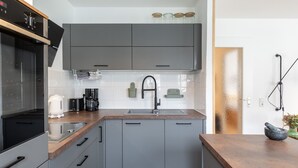 A modern kitchen with grey cabinets, a stainless steel sink, and a coffee maker. - 3 rooms apartment- 4 people (Leipzig)