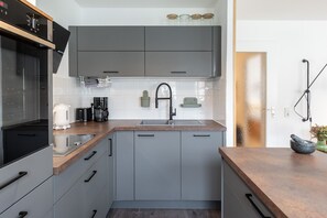 A modern kitchen with grey cabinets, a stainless steel sink, and a coffee maker.
