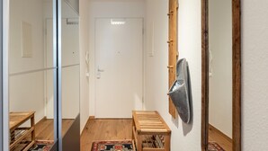 Un pasillo con un banco de madera, un espejo y una puerta.