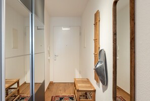 A hallway with a wooden bench, a mirror, and a door.