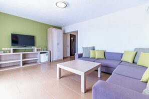 Una sala de estar moderna con una televisión de pantalla plana, un sofá, una mesa de centro y un mueble.