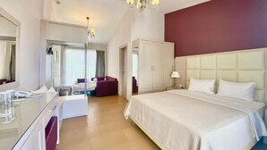 Habitació d'hotel amb un llit gran, una tocador amb mirall, una zona de seients i un penjador.