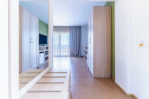 Un corridoio con pavimento in legno, una televisione su uno scaffale e una finestra con tende.