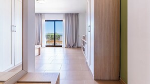 Een gang met uitzicht op een balkon, een houten garderobe en een bank.