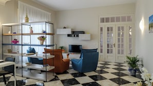 Una sala de estar con piso de cuadros, un televisor, un sofá y una estantería.