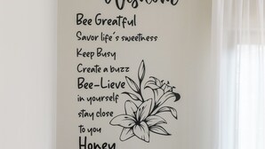 Una cocina con un adhesivo mural que dice 'Bee Wisdom' y una mesa con diversos alimentos.
