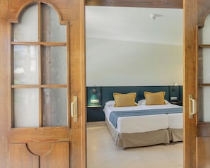 A hotel room with a bed, a nightstand, a wall-mounted lamp, and a wooden door with glass panels. - Hotiday Gran Canaria Maspalomas (San Bartolome de Tirajana)