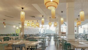 A spacious dining area with multiple tables and chairs, featuring a modern design with hanging wicker chandeliers and a large window providing natural light. - Hotiday Gran Canaria Maspalomas (San Bartolome de Tirajana)