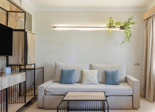 A modern living room with a sofa, a coffee table, and a mounted TV. - Hotiday Gran Canaria Maspalomas (San Bartolome de Tirajana)