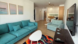 Una sala de estar moderna con sofás color turquesa, una mesa de centro blanca y una alfombra colorida.