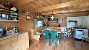 Een knus houten blokhut interieur met een eethoek, houten kastjes en een open haard.
