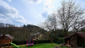 A backyard with a wooden playhouse, a pink trampoline, and a tree. - Beautiful private villa with WIFI, private pool, TV, terrace, pets allowed and panoramic view (Semily)