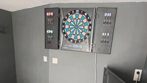 A room with grey walls, a dartboard, a television, and a small black cabinet. - Apartment with exterior (Mirebeau)