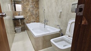 A modern bathroom with a bathtub, a sink, and a bidet. - Hotel Nexus Inn (Ahmedabad)