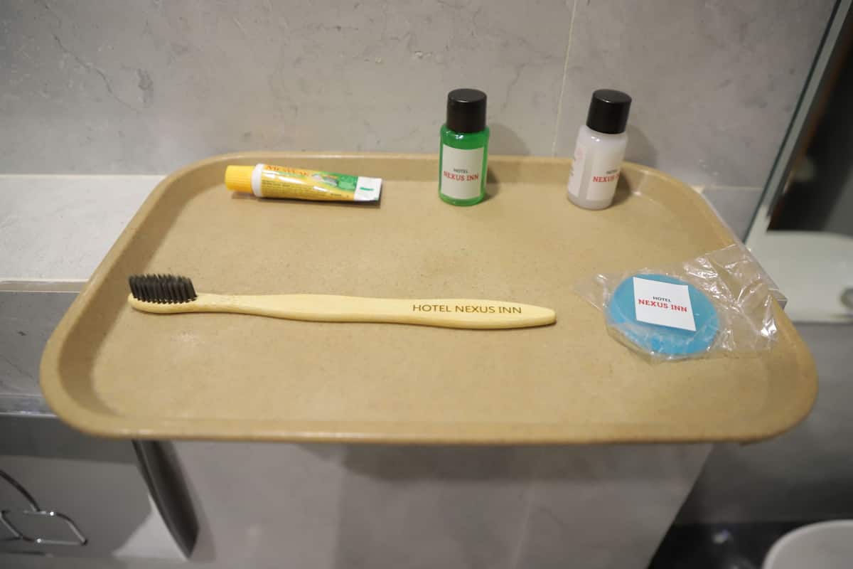 A bathroom counter with toiletries including a toothbrush, a green bottle, a white bottle, and a blue soap bar.