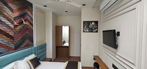 A hotel room with a bed, a TV, a mirror, and a colorful wall mural. - Hotel Nexus Inn (Ahmedabad)