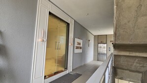 A hallway with a closed elevator, a sign indicating 'Hotel Reception', and a door with a golden curtain. - Hotel Nexus Inn (Ahmedabad)