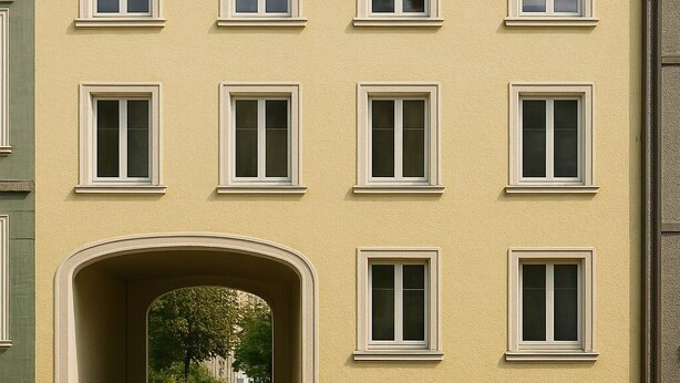 A two-story building with a yellow facade, multiple windows, and a central archway.