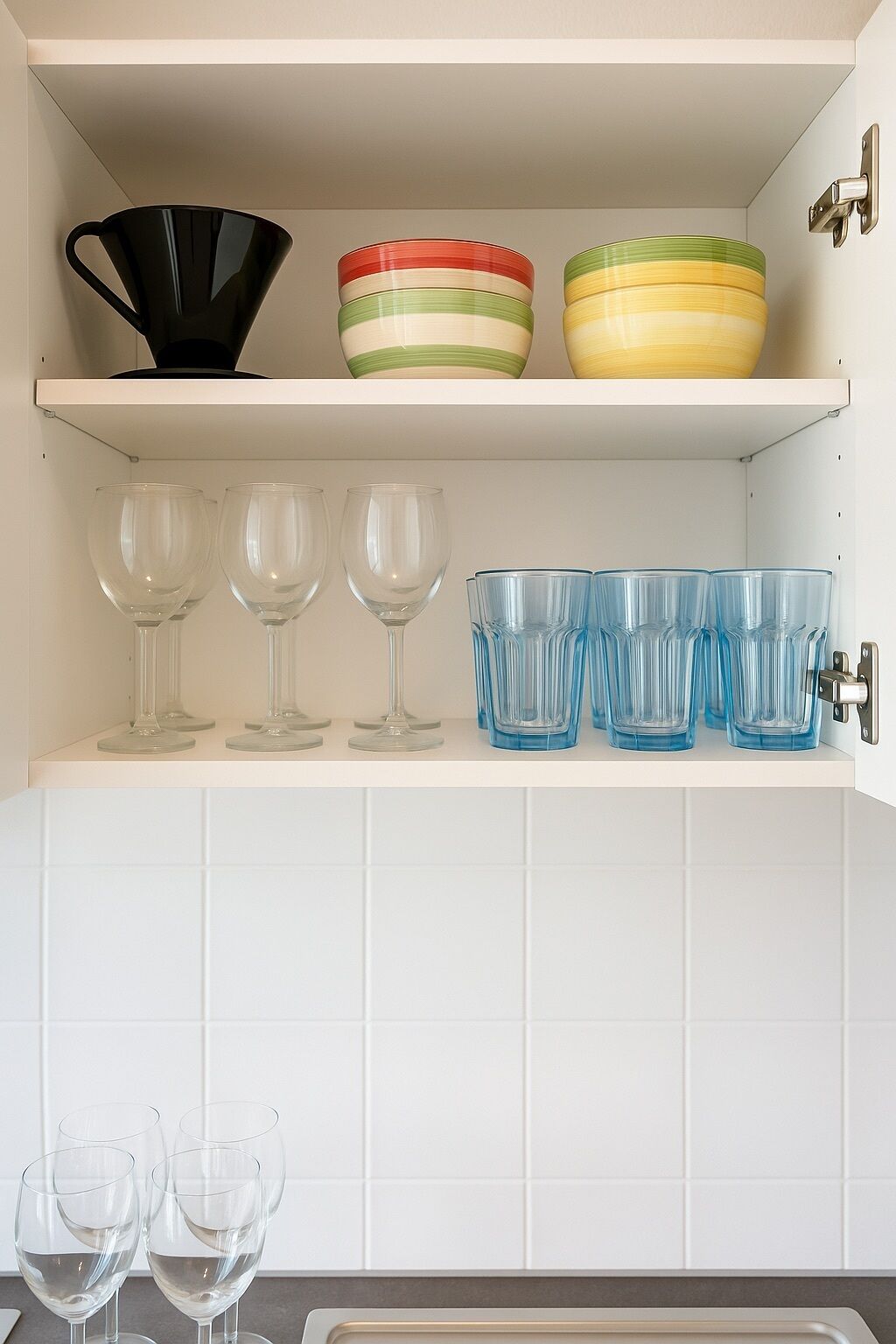 A kitchen shelf with various glassware and bowls.