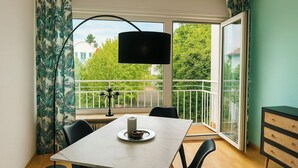 A dining area with a table, chairs, a candle holder, and a view of a balcony with greenery.