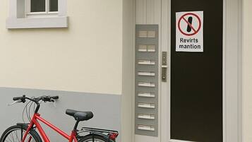 A red bicycle parked in front of a door with a 'Reverts mention' sign.