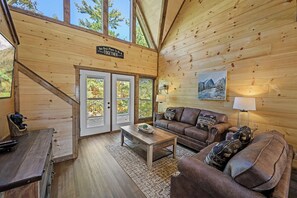 L’intérieur d’un chalet en bois, avec un canapé, une table basse et un panneau accroché au mur.