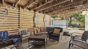 An outdoor patio area with wicker furniture, a grill, and a wooden ceiling. - Bombastic Bungalow Beach Home, just a 9 minute walk from the beach! (Panama City Beach)
