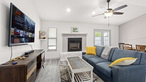 A living room with a TV, fireplace, sofa, and ceiling fan.