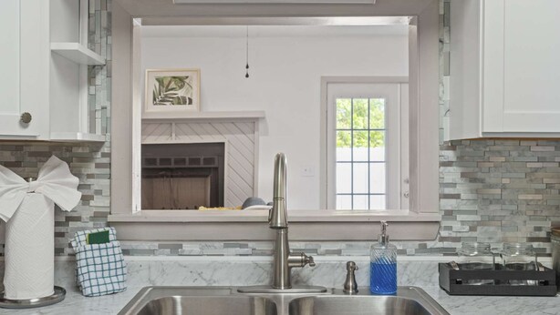 A kitchen with a double sink, a window, and a fireplace.