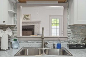 Una cocina con un lavamanos doble, una ventana y una chimenea.