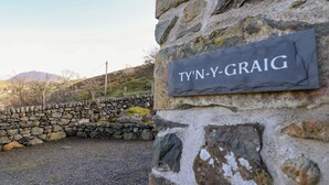 Un mur de pierres sur lequel est apposée une plaque indiquant « TY’N-Y-GRAIG ».