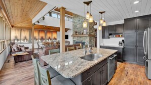 A spacious kitchen with a large island, dark cabinetry, and a stone accent wall. - Lake Front - Spacious - Outdoor (Albrightsville)