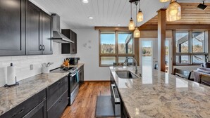 A modern kitchen with dark cabinets, a large island, and pendant lighting. - Lake Front - Spacious - Outdoor (Albrightsville)