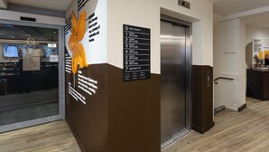 Zona de recepció d'hotel amb una pantalla digital que mostra el número 0, un senyal d'indicació amb els números de les habitacions i un senyalitzador per a personal.