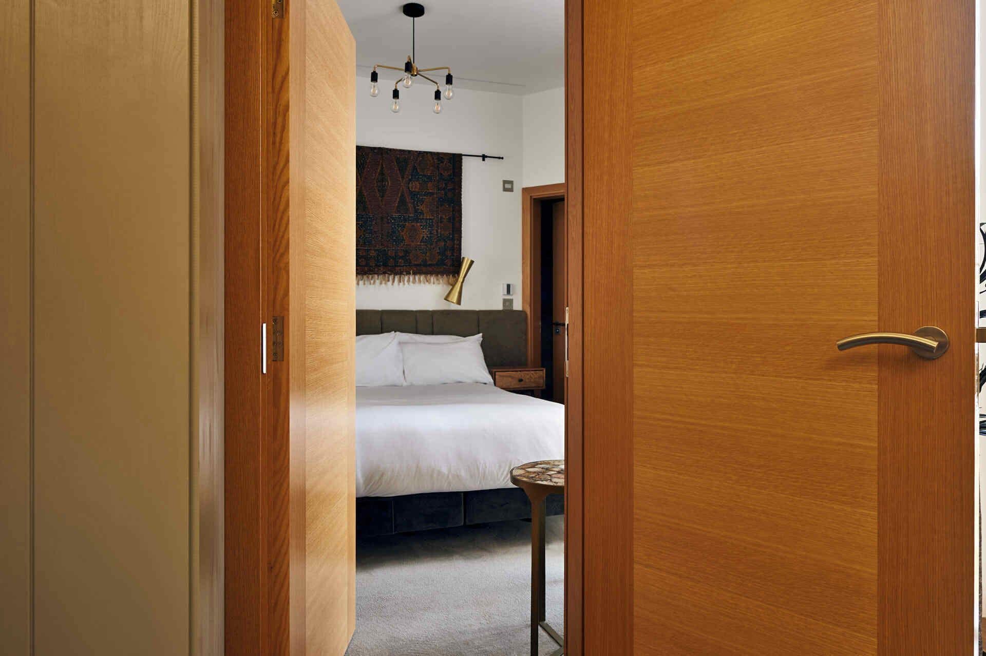 Une chambre à coucher avec un lit, une table de chevet, une lampe et une tapisserie à motifs accrochée au mur.
