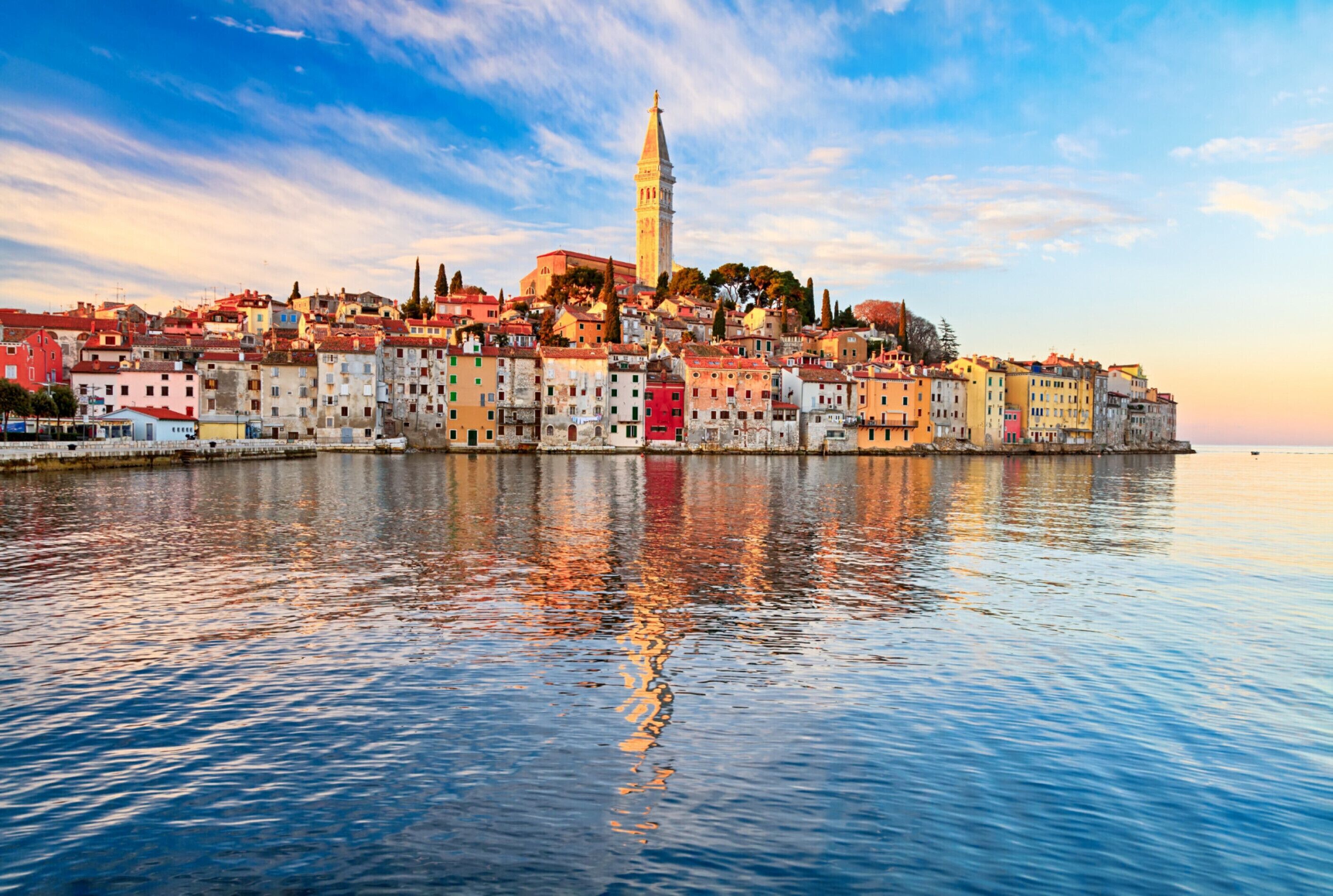 A coastal cityscape with a prominent tower and colorful buildings along the waterfront.