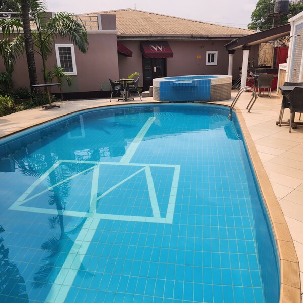 A swimming pool with tiled flooring and a clear blue water surface. - HOD APARTMENTS   GRA  (Lagos)