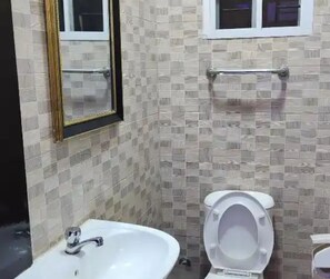 A bathroom with a white sink, a toilet, and a mirror. - HOD APARTMENTS   GRA  (Lagos)