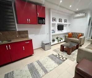 A modern living room with a red kitchen, a grey sofa, and a coffee table.