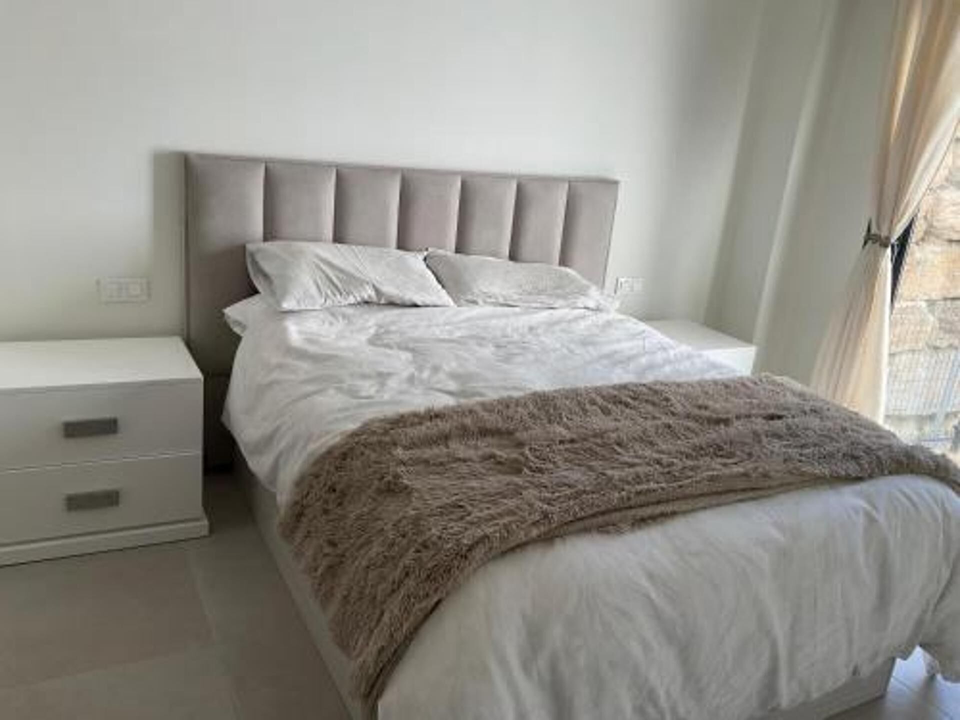 A bedroom with a bed, a nightstand, and a dresser.