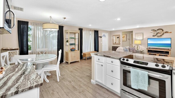A modern kitchen with a marble countertop, white cabinetry, and a built-in oven. - Tranquil Pool Home Near Siesta Key (Sarasota)