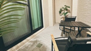 Un patio moderno con una porta a vetri, un tavolo, sedie e una pianta in vaso.