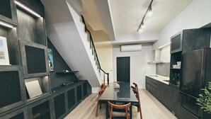 Una cucina moderna con mobili scuri, un'isola centrale e un'area pranzo con sedie in legno.
