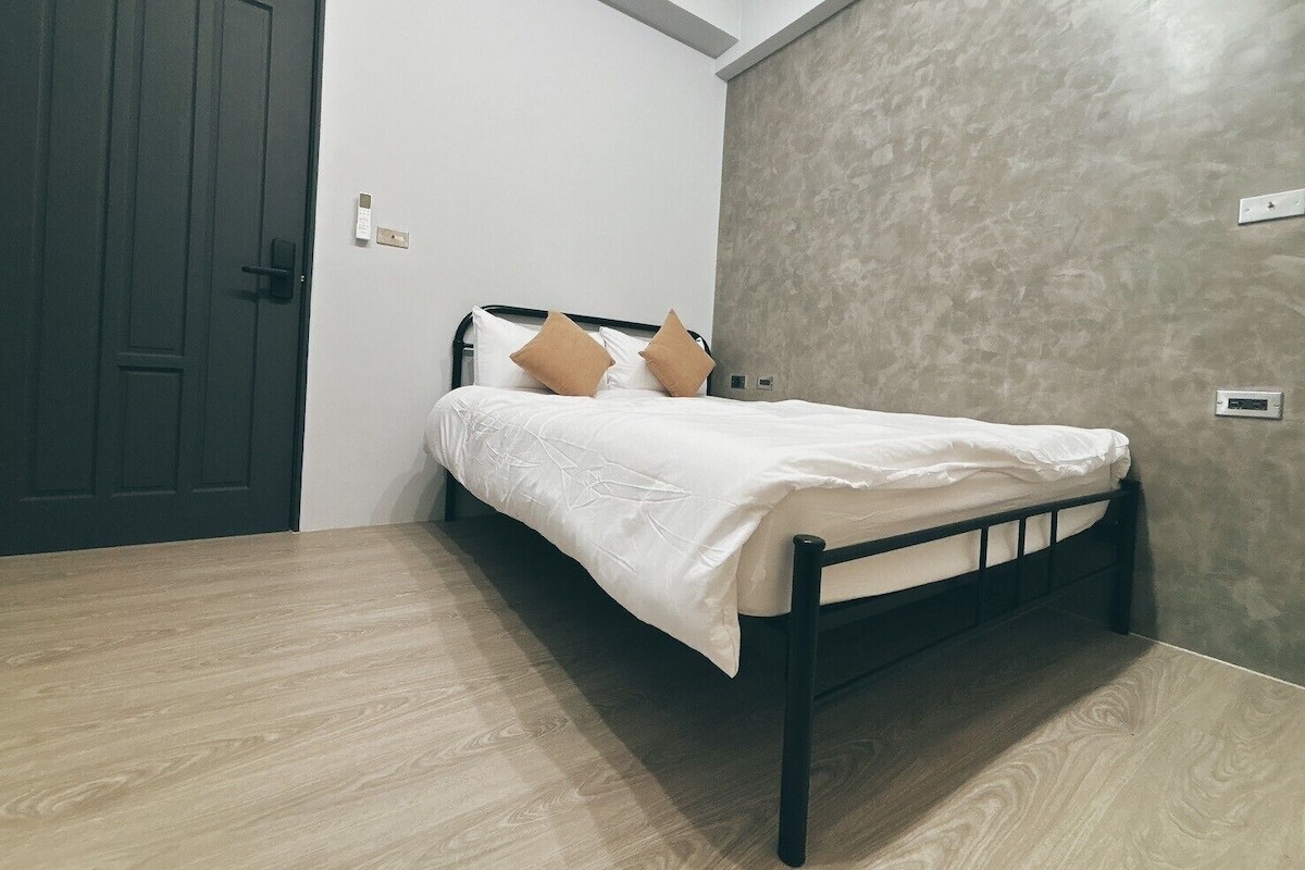 A bedroom with a bed, a door, and a textured wall.