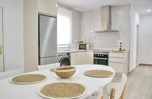 A modern kitchen with stainless steel appliances, a dining table with woven placemats, and a clean, minimalist design.