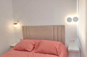 Ein Bett mit Kopfteil, zwei Nachttischen und Wandleuchten.