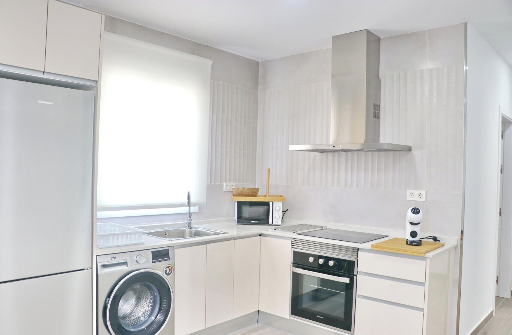 A modern kitchen with a washing machine, oven, microwave, and a built-in stove.