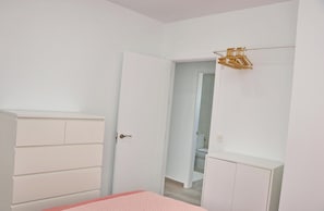 A room with a bed, a wardrobe, and a door leading to a bathroom.