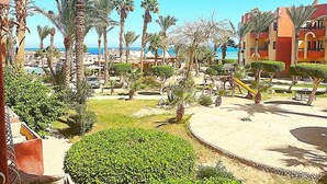 Ein Feriengebiet mit Palmen, einem Pool und Blick auf das Meer.